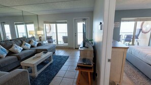 Een woonkamer met een bank, salontafel, televisie en een balkon met tuinmeubilair.