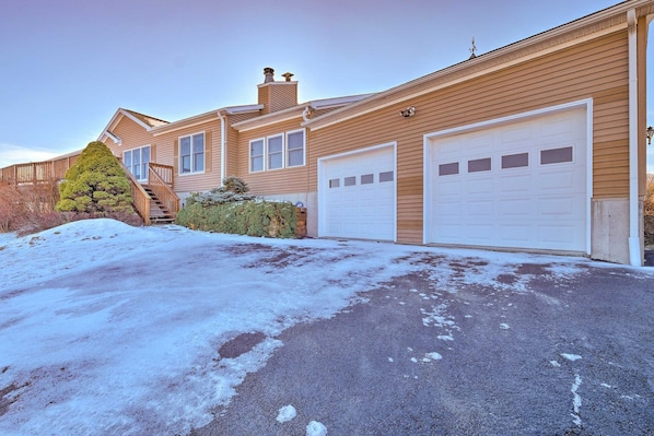 A residential property with a garage, a staircase, and a snow-covered driveway.