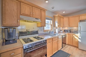 A kitchen with wooden cabinets, a gas stove, a microwave, and a refrigerator.