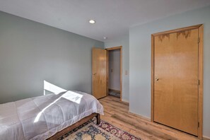 Une chambre à coucher avec un lit, une armoire en bois et une porte donnant sur une autre pièce.