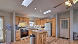 A modern kitchen with wooden cabinets, a central island, a built-in oven, and a refrigerator.