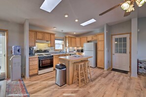A modern kitchen with wooden cabinets, a central island, a built-in oven, and a refrigerator.