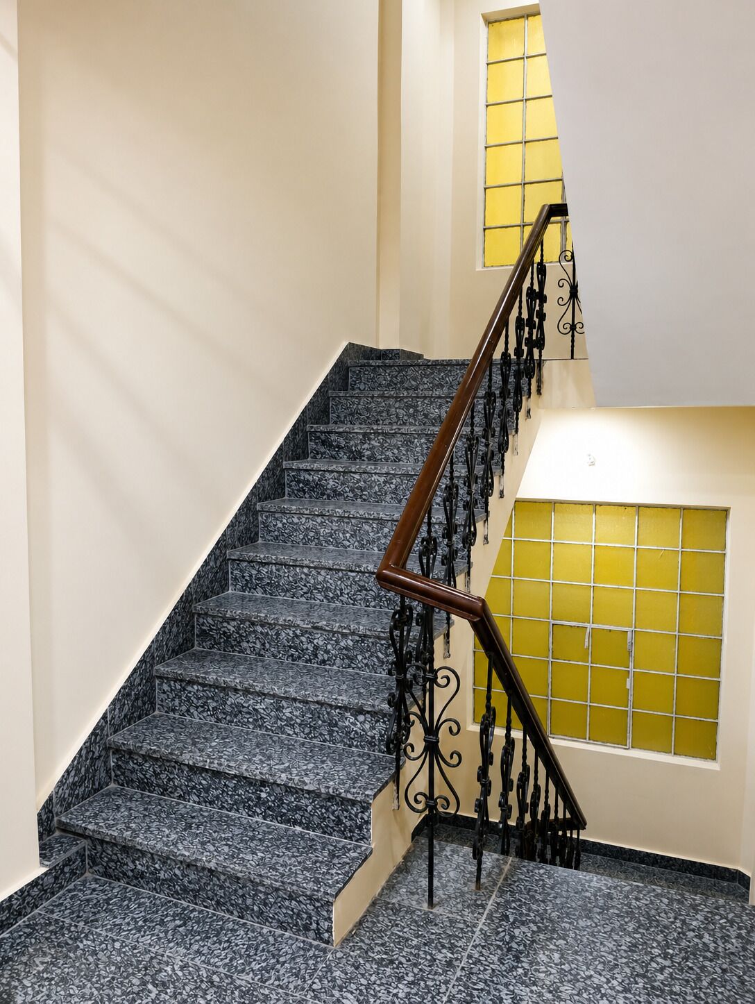 A staircase with a handrail and a window with yellow-tinted glass.