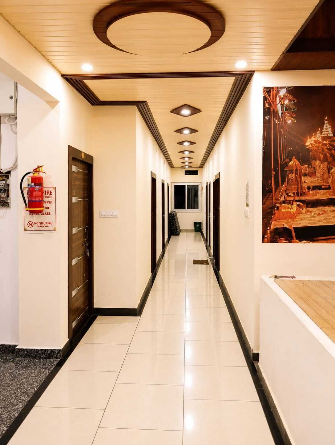 A hotel hallway with a fire extinguisher, a no smoking sign, and a poster on the wall.