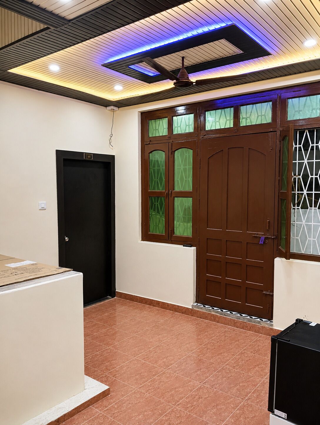 A room with a tiled floor, a brown door with glass panels, and a ceiling with recessed lighting.