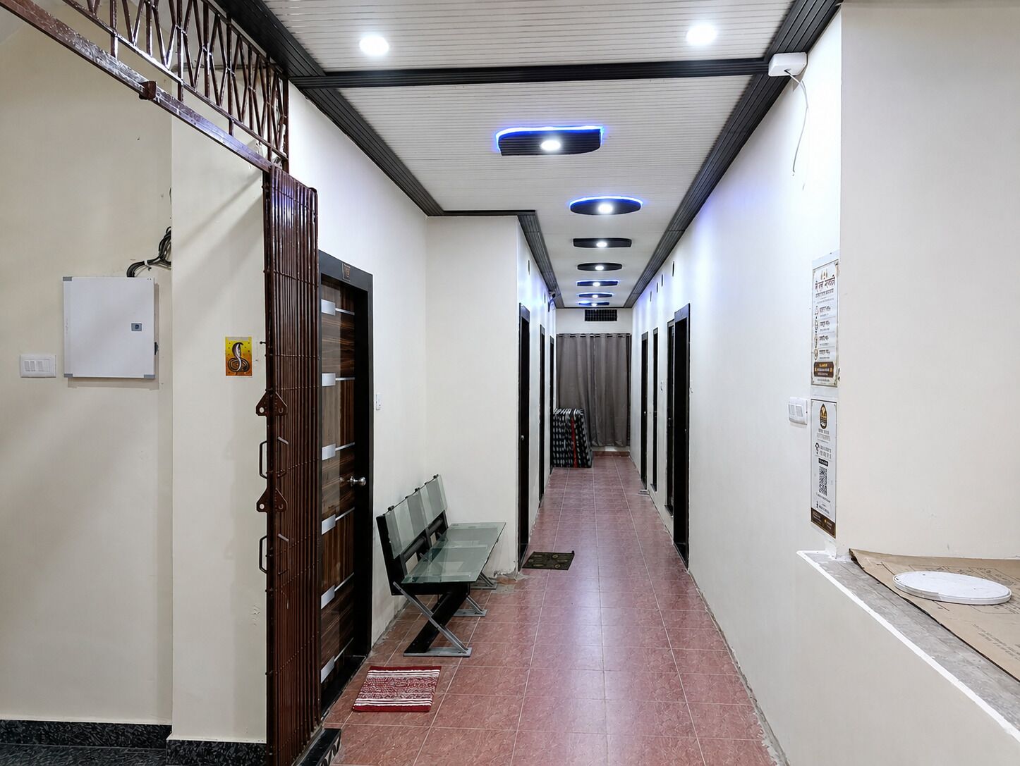 Um corredor com porta de madeira, um banco e chão de azulejos.
