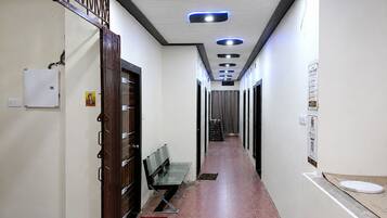 A hallway with a wooden door, a bench, and a tiled floor.