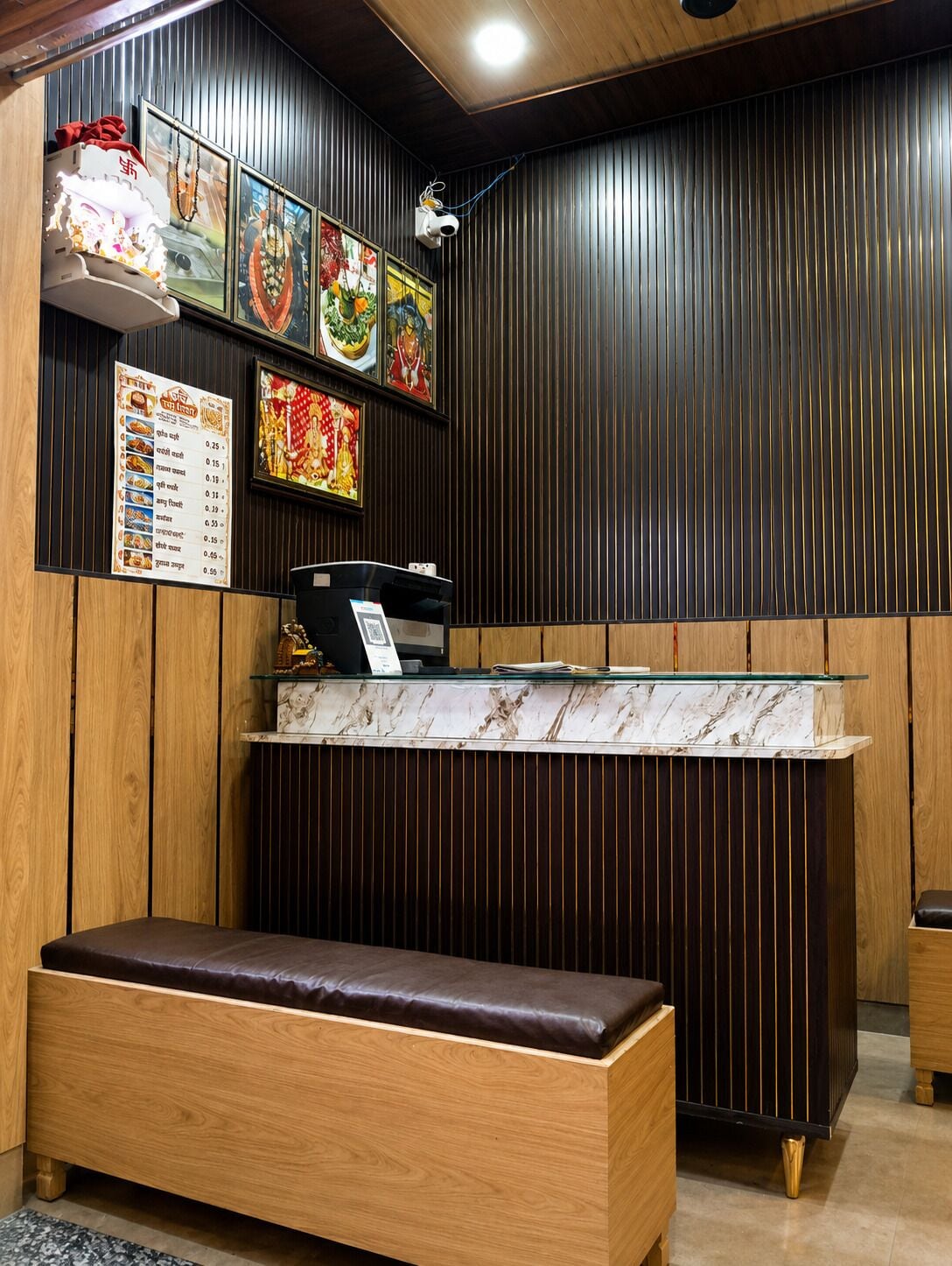 Een restaurantinterieur met een houten bank, een toonbank met een menukaart en decoratieve wandkunst.