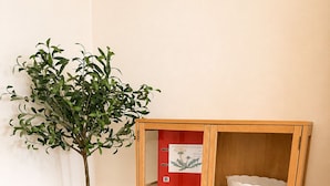 Un meuble en bois avec des portes en verre, une plante en pot et un dossier rouge posé sur le dessus.