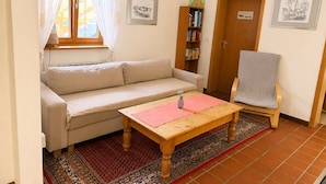 Un salon avec un canapé, une table en bois, une bibliothèque et une porte.