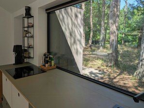 A modern kitchen with a large window overlooking a forested area. - Modern oasis in the middle of the forest in Rørvig (Rørvig)