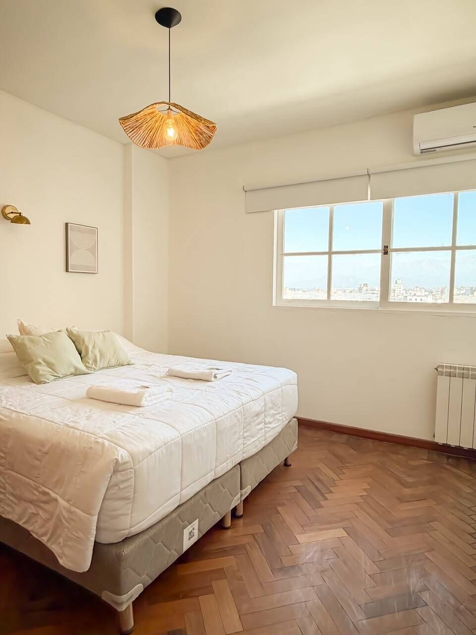 Ein Schlafzimmer mit einem Bett, einem Fenster, einer Heizung und einer Pendelleuchte.