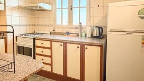 Una cucina con piano cottura, frigorifero e finestra.