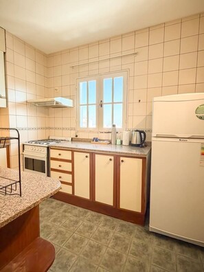 Una cocina con estufa, refrigerador y ventana.