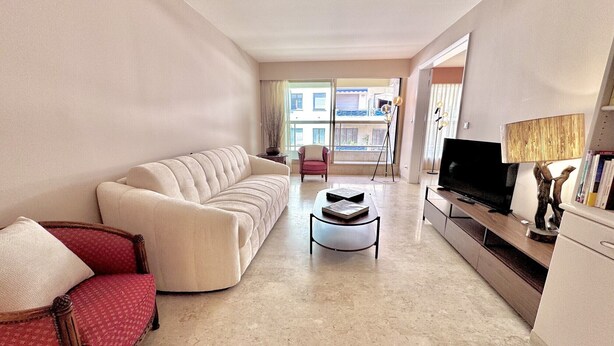 Ein modernes Wohnzimmer mit Sofa, Sessel, Couchtisch, Fernseher und Dekorationselementen.