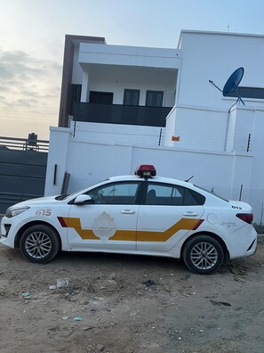 A white car with yellow and red markings parked in front of a building with a satellite dish. - A premium apartment in the heart of Ibadan, offering comfort and convenience. (Ibadan)