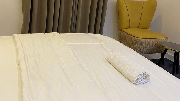 A hotel room with a bed, a chair, and a curtain. - A premium apartment in the heart of Ibadan, offering comfort and convenience. (Ibadan)