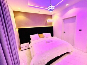 Un dormitorio moderno con una cama grande, una lámpara de techo y una puerta.