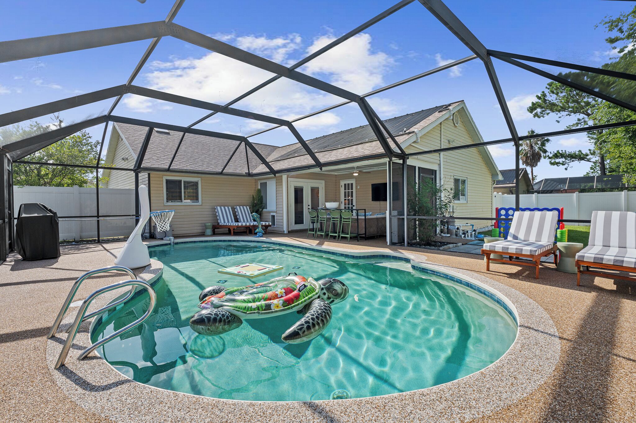 Piscina com área coberta, espreguiçadeiras e um pequeno deck.