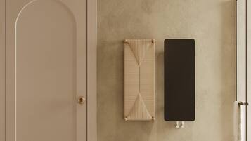 Un baño minimalista con una puerta color beige, una pared con textura, un perchero, un lavabo y un pequeño jarrón con plantas secas.