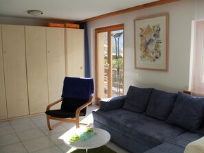 Ein Wohnzimmer mit einer Couch, einem Sessel, einem kleinen Tisch und einem Kleiderschrank.