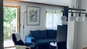 A modern living room with a sofa, a dining table, and a chair. There is a painting on the wall and a lamp. - Chalet Solana 1 # 2-bed apartment, Bad, WC 2-Bettwohnung, Bad, WC by Interhome (Leukerbad)