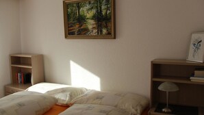 A bedroom with a bed, a nightstand, a bookshelf, and a painting on the wall. - Chalet Solana 1 # 2-bed apartment, Bad, WC 2-Bettwohnung, Bad, WC by Interhome (Leukerbad)