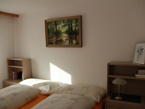 A bedroom with a bed, a nightstand, a bookshelf, and a painting on the wall. - Chalet Solana 1 # 2-bed apartment, Bad, WC 2-Bettwohnung, Bad, WC by Interhome (Leukerbad)