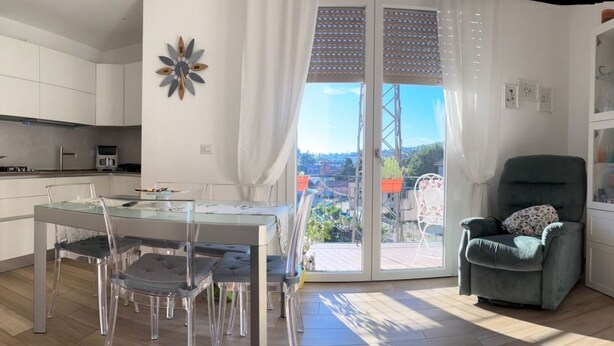 A modern kitchen with white cabinets, a dining area with a glass table and chairs, and a balcony with a view. - Your Lake Como getaway (Casa Amata) (Cernobbio)