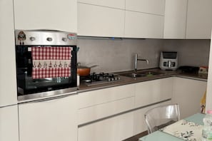 Een keuken met een fornuis, oven en magnetron.