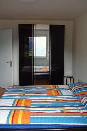 A bedroom with a bed, a wardrobe, and a window. - Gochty 12M # 4-bed apartment, Bad, WC 4-Bettwohnung, Bad, WC by Interhome (Leukerbad)