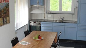 Eine moderne Küche mit blauen Schränken, einem Holztisch und einem Fenster mit Blick auf Grünflächen.