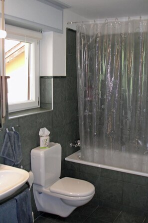 A bathroom with a toilet, sink, and bathtub. - Gochty 12M # 4-bed apartment, Bad, WC 4-Bettwohnung, Bad, WC by Interhome (Leukerbad)
