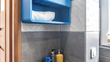A bathroom with a green sink, a blue faucet, a mirror, and a towel.