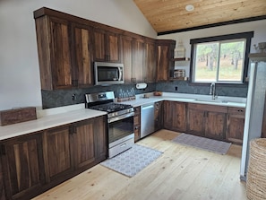 Une cuisine moderne avec des meubles en bois, des appareils électroménagers en acier inoxydable et une grande fenêtre donnant sur l’extérieur.