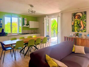 A modern kitchen with a dining area, a sofa, and a large window with a view of greenery. - Villa with pool and jacuzzi on the Garda Lake (Manerba del Garda)