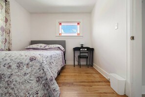 Un dormitorio con una cama, un escritorio y una ventana.