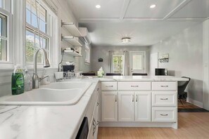 Una cocina moderna con armarios blancos, encimera de mármol y lavavajillas integrado.