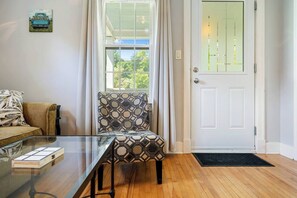 A room with a glass table, patterned armchair, and a white door.