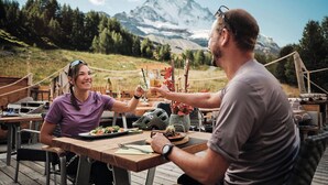 Ein Esstisch mit Mahlzeit, einem Helm und Blick auf die Berge im Hintergrund.