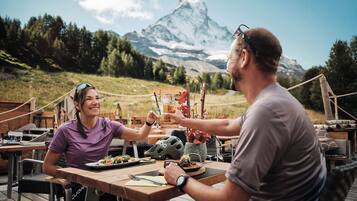 Ein Esstisch mit Mahlzeit, einem Helm und Blick auf die Berge im Hintergrund.