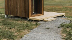 Uma cabana de madeira com porta e um pequeno alpendre.