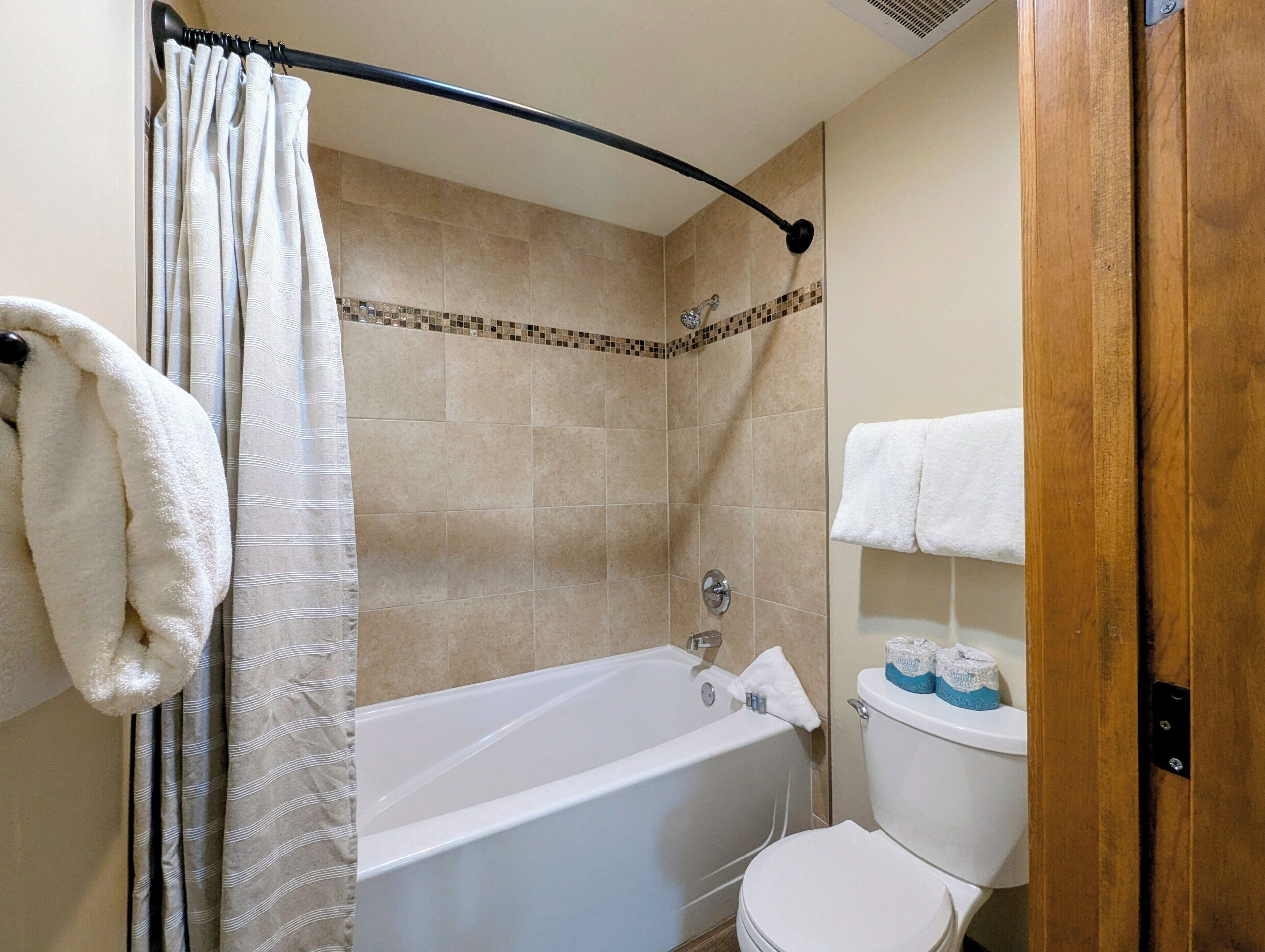 A bathroom with a bathtub, toilet, and shower curtain.