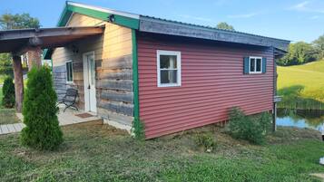 A log cabin with a green roof, a door, and a window.