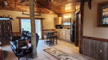 A cozy interior with a leather sofa, a dining area, and a kitchen with wooden cabinets.