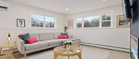 A modern living room with a grey sofa, a round coffee table, and a white rug.