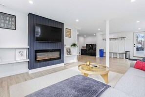 Una sala de estar moderna con chimenea, televisor de pantalla plana y una zona de estar con una mesita de centro.
