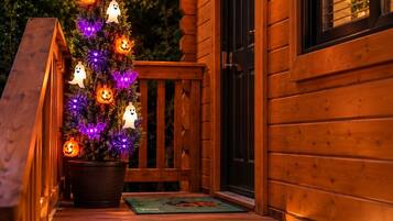 Une cabane en bois avec un porche, un sapin de Noël illuminé et une porte.