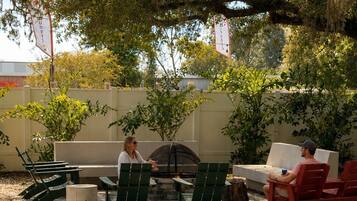 Un espace extérieur aménagé avec des chaises et une table, entouré d’arbres et recouvert d’un sol en gravier.