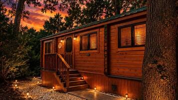A wooden cabin with a staircase, windows, and a porch area.